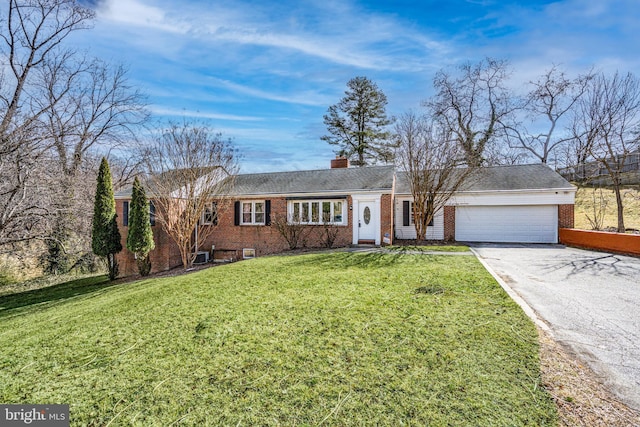 ranch-style home featuring brick siding, a chimney, an attached garage, a front yard, and driveway