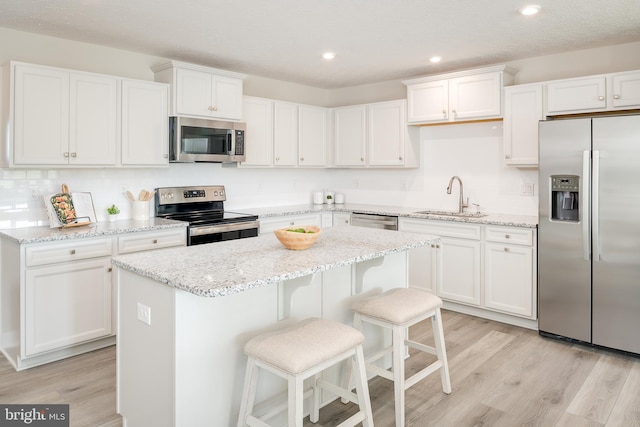 kitchen with sink, stainless steel appliances, a center island, and white cabinets