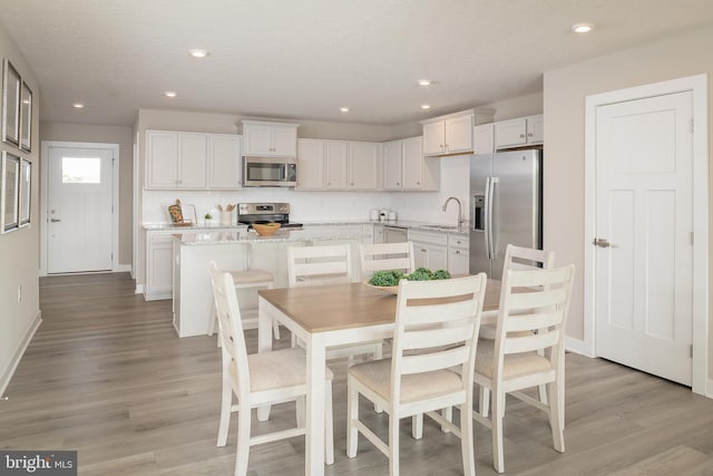 dining area featuring sink, a textured ceiling, and light wood-type flooring