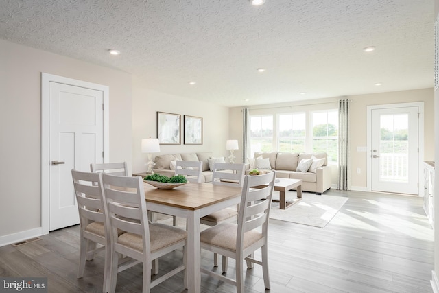 dining space featuring a textured ceiling and light hardwood / wood-style floors