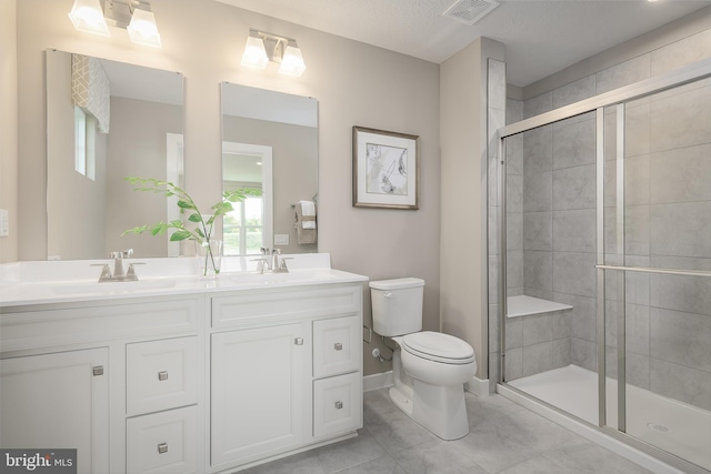 bathroom with a shower with door, vanity, tile patterned floors, and toilet