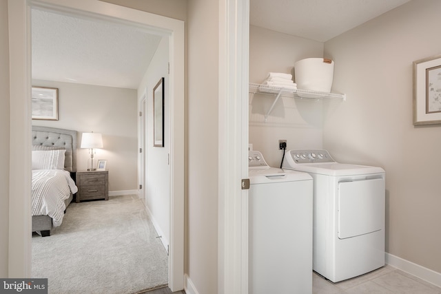 washroom featuring laundry area, light carpet, baseboards, and washer and clothes dryer