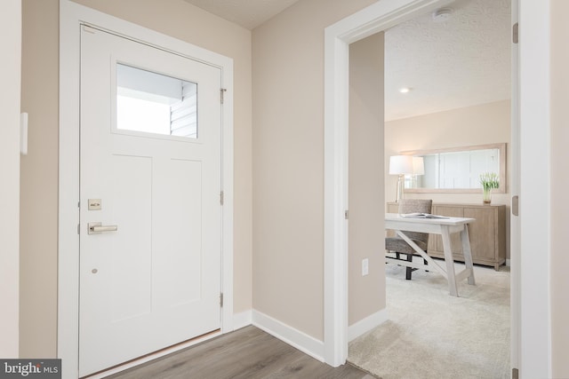 carpeted entryway featuring baseboards and a textured ceiling