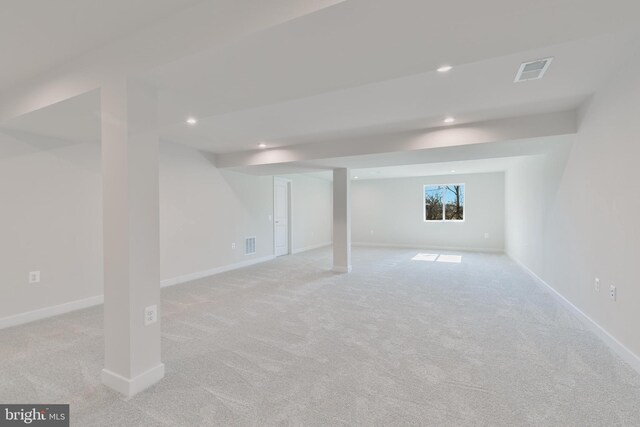 below grade area with light carpet, recessed lighting, visible vents, and baseboards