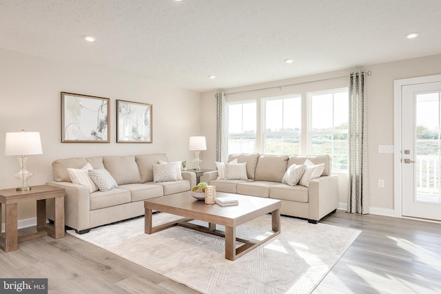 living room with recessed lighting, baseboards, light wood finished floors, and a textured ceiling