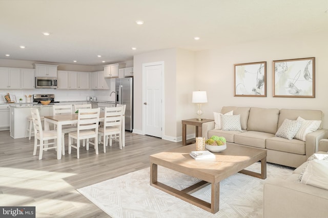 living room featuring sink and light hardwood / wood-style flooring