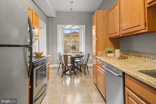 kitchen featuring light stone counters, hanging light fixtures, light tile patterned floors, and stainless steel appliances