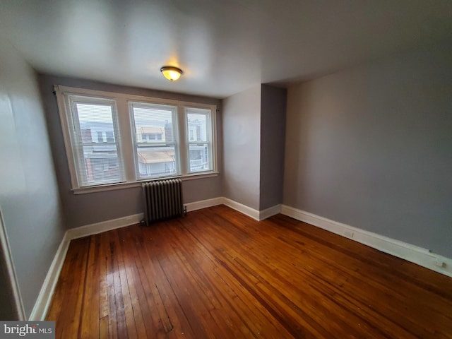 empty room featuring radiator heating unit and dark hardwood / wood-style floors