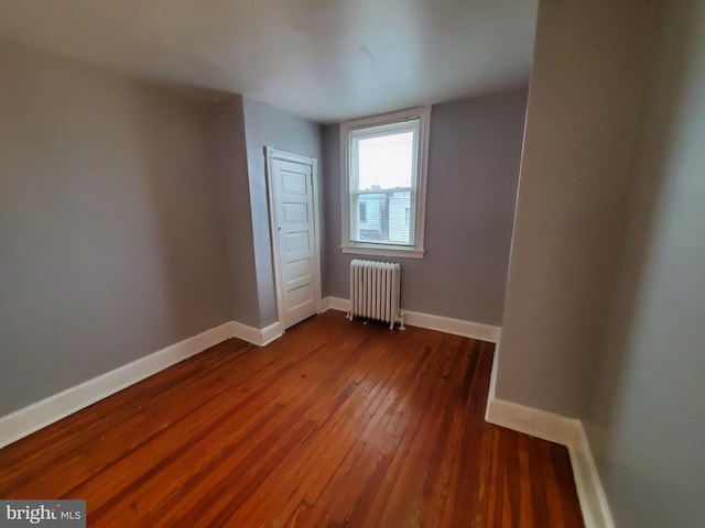 unfurnished room with dark hardwood / wood-style flooring and radiator heating unit