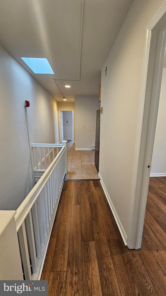 hall featuring hardwood / wood-style flooring and a skylight