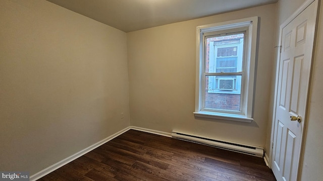 unfurnished room with a healthy amount of sunlight, a baseboard heating unit, and dark hardwood / wood-style floors