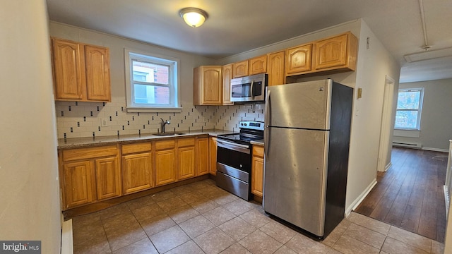 kitchen with a healthy amount of sunlight, appliances with stainless steel finishes, sink, and a baseboard heating unit