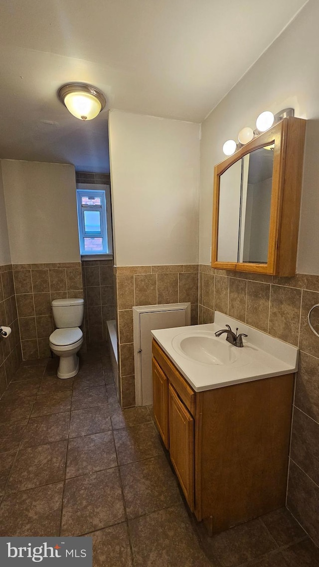 bathroom featuring vanity, toilet, and tile walls