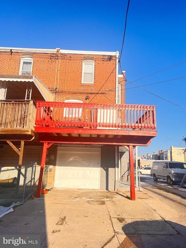 rear view of house with a wooden deck, a garage, and a balcony