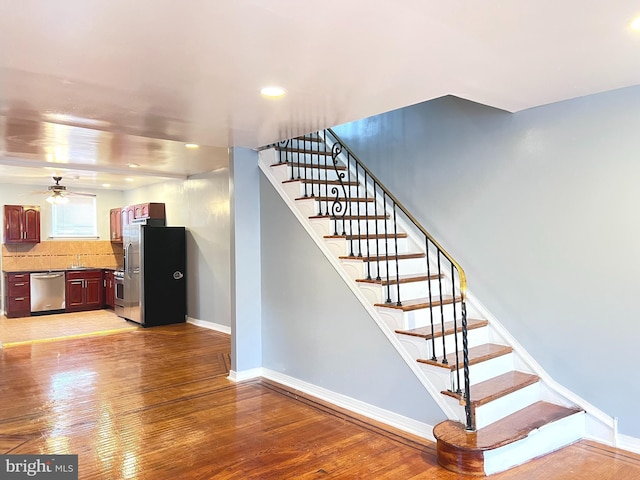 stairway with sink, hardwood / wood-style floors, and ceiling fan