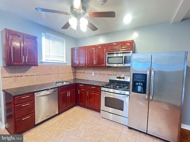 kitchen featuring appliances with stainless steel finishes, sink, dark stone counters, and decorative backsplash