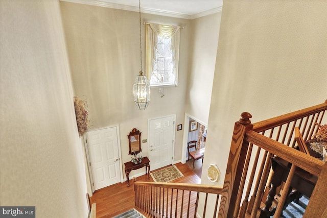 foyer featuring stairway, ornamental molding, wood finished floors, a chandelier, and baseboards