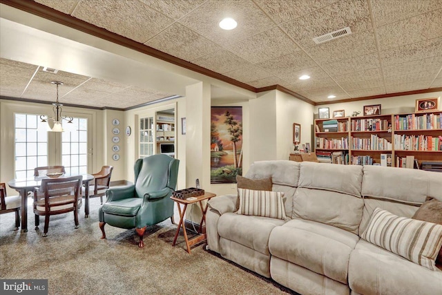 living area featuring ornamental molding, carpet, visible vents, and an inviting chandelier