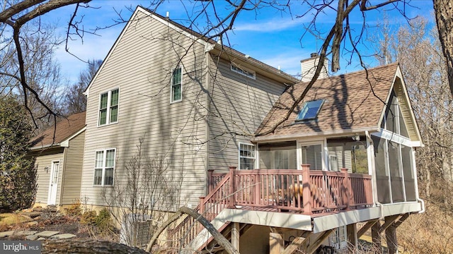 view of property exterior featuring roof with shingles, a chimney, a sunroom, a deck, and stairs