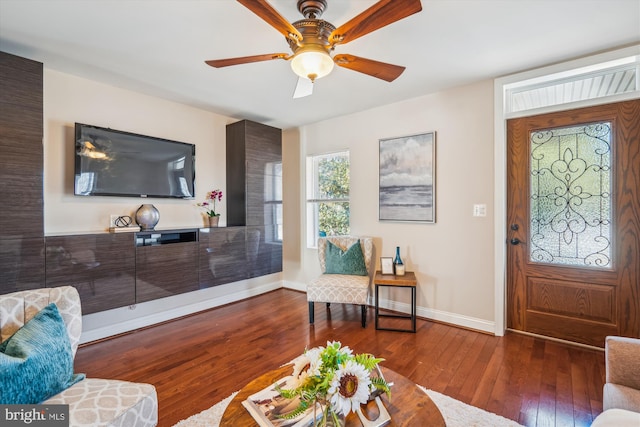 living area featuring hardwood / wood-style floors, a ceiling fan, and baseboards