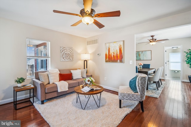 living area featuring visible vents, baseboards, dark wood-style floors, and ceiling fan