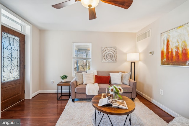 living area with visible vents, baseboards, dark wood-type flooring, and ceiling fan