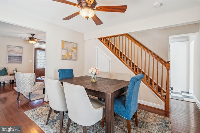 dining space with stairway, baseboards, dark wood-style flooring, and a ceiling fan