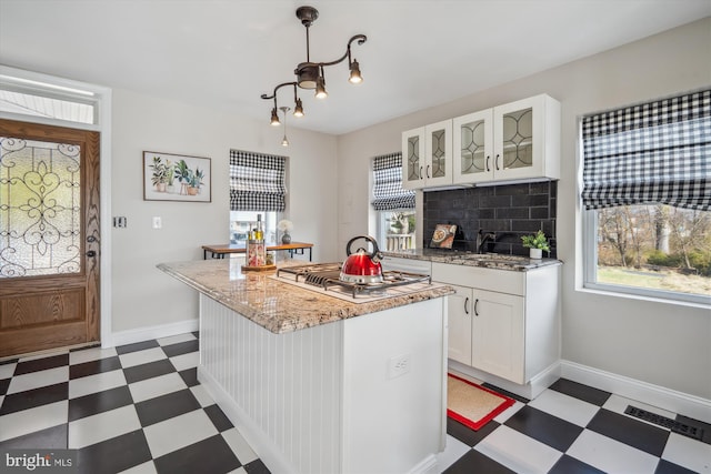 kitchen featuring visible vents, white gas cooktop, glass insert cabinets, and dark floors