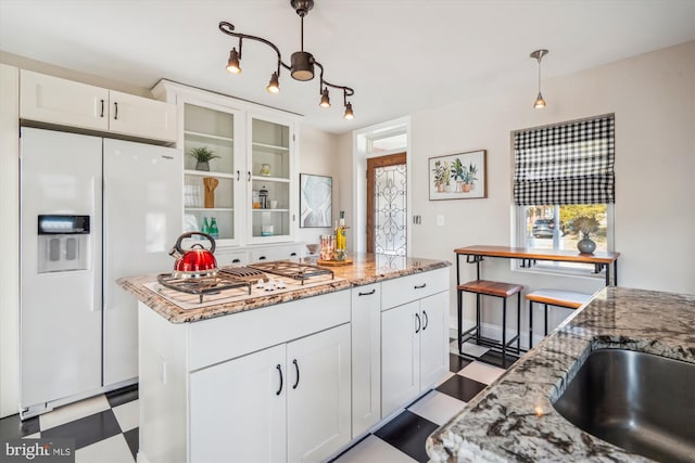 kitchen with light stone countertops, decorative light fixtures, tile patterned floors, white cabinets, and white appliances