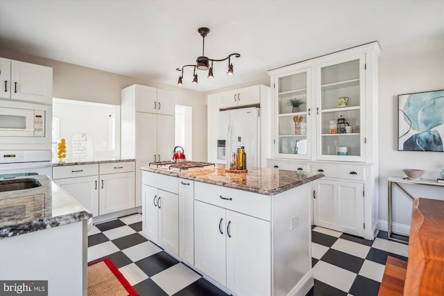 kitchen featuring white cabinets, white appliances, a center island, and dark floors