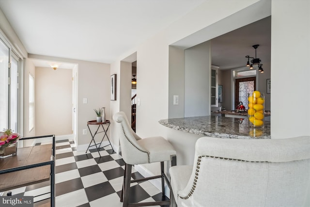 kitchen featuring tile patterned floors, stone counters, and baseboards