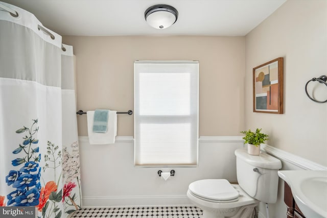 full bathroom featuring vanity, a shower with shower curtain, toilet, and baseboards