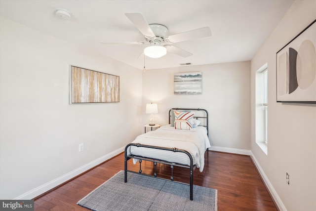 bedroom featuring ceiling fan, visible vents, baseboards, and wood finished floors