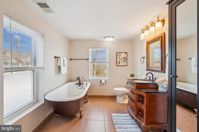 bathroom featuring visible vents, baseboards, a freestanding tub, tile patterned floors, and vanity