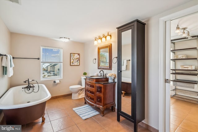 full bathroom featuring tile patterned flooring, a soaking tub, toilet, and vanity