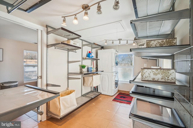 kitchen with light tile patterned floors, stacked washer / dryer, and rail lighting