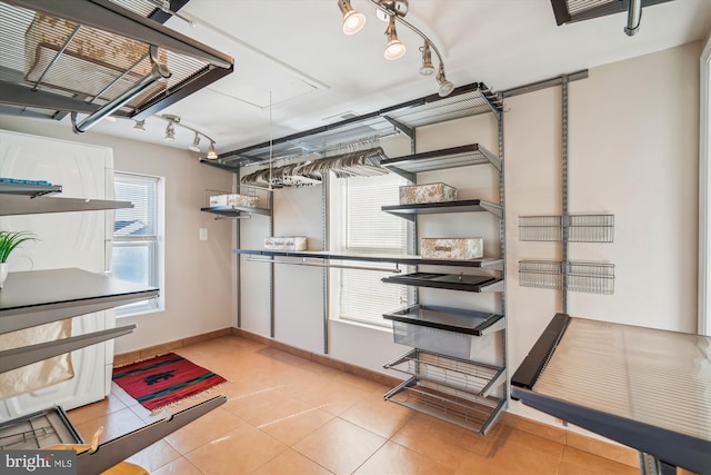 interior space with rail lighting, light tile patterned floors, and baseboards