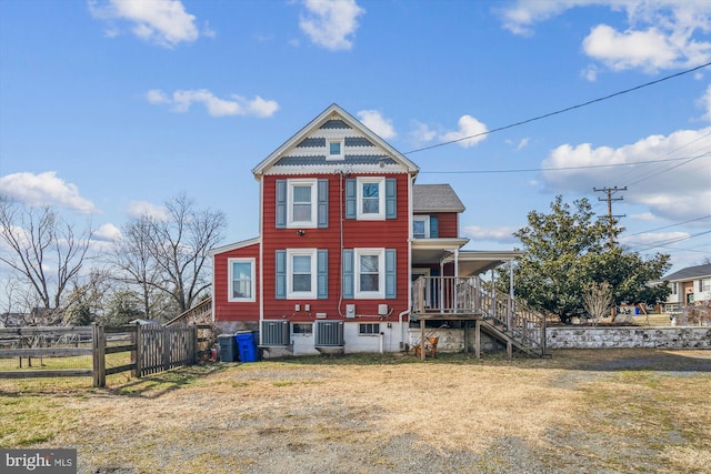 view of front of house featuring a front yard, stairs, central AC, and fence