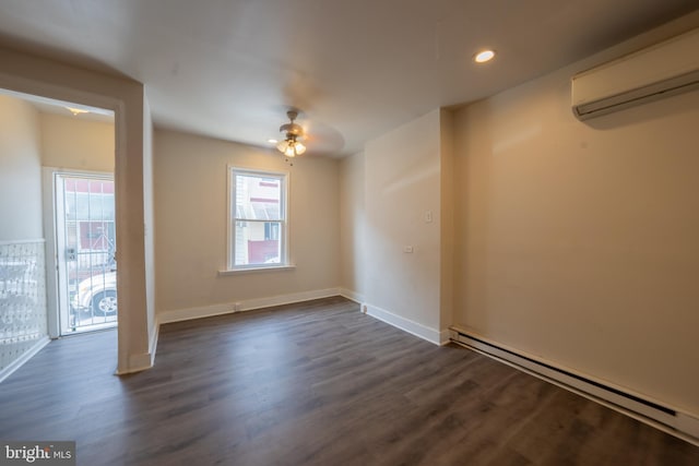 empty room featuring an AC wall unit, a baseboard heating unit, a wealth of natural light, and dark hardwood / wood-style flooring