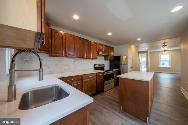 kitchen with sink, appliances with stainless steel finishes, backsplash, a center island, and dark hardwood / wood-style flooring