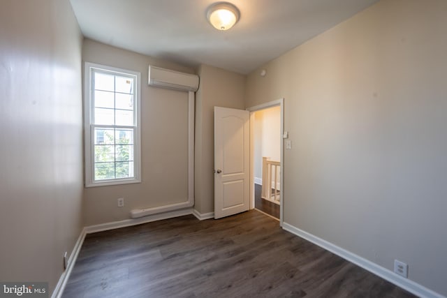 unfurnished bedroom featuring a wall mounted air conditioner and dark hardwood / wood-style floors