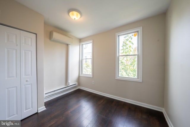 unfurnished bedroom with a closet, dark wood-type flooring, an AC wall unit, and baseboard heating