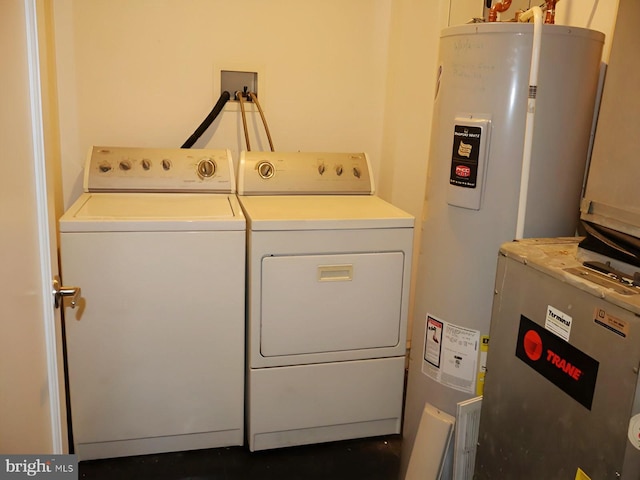 clothes washing area featuring water heater, laundry area, and independent washer and dryer