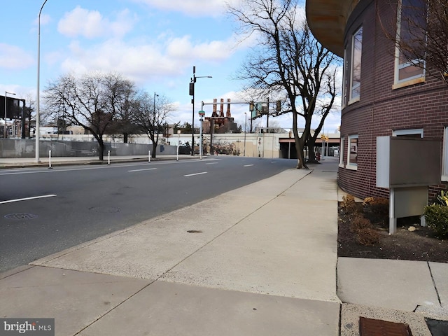 view of street featuring sidewalks, traffic lights, street lighting, and curbs