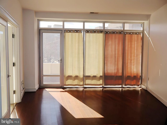 interior space with dark wood-style floors, visible vents, and baseboards