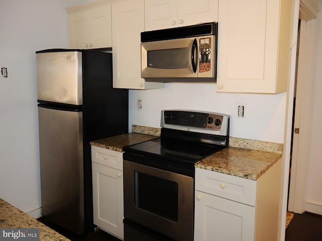 kitchen featuring appliances with stainless steel finishes, stone countertops, and white cabinetry