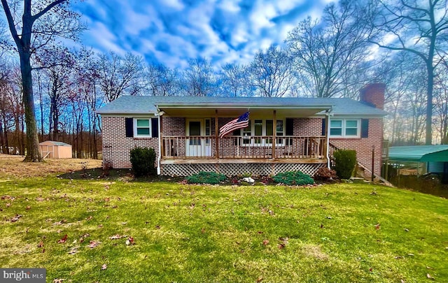 single story home with a porch, a storage unit, and a front yard