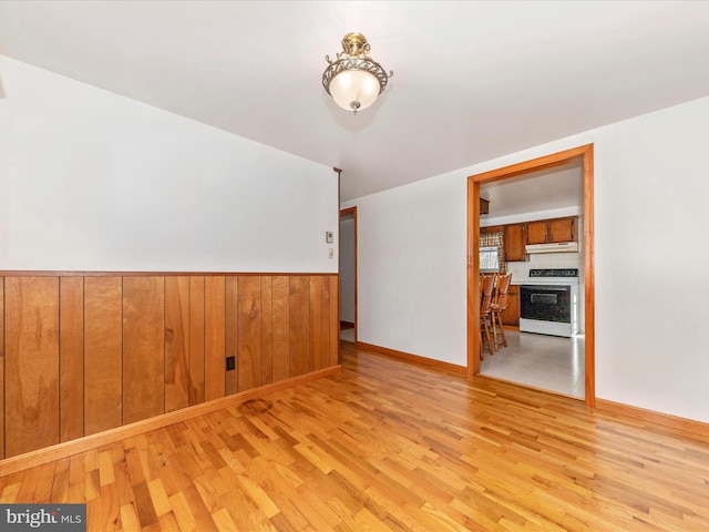 spare room with light hardwood / wood-style floors and wood walls