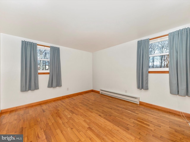 unfurnished room featuring a baseboard radiator, plenty of natural light, and light hardwood / wood-style flooring