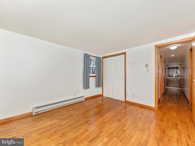 unfurnished bedroom featuring light hardwood / wood-style floors, a closet, and a baseboard heating unit